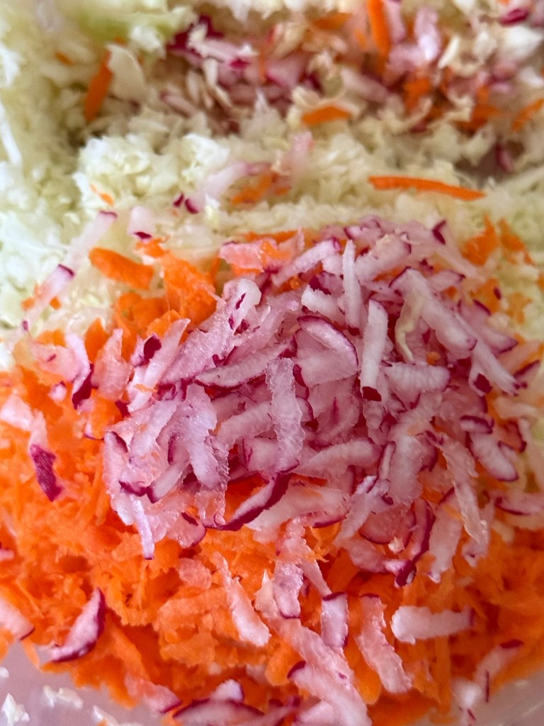 A close-up of grated carrots and red radishes